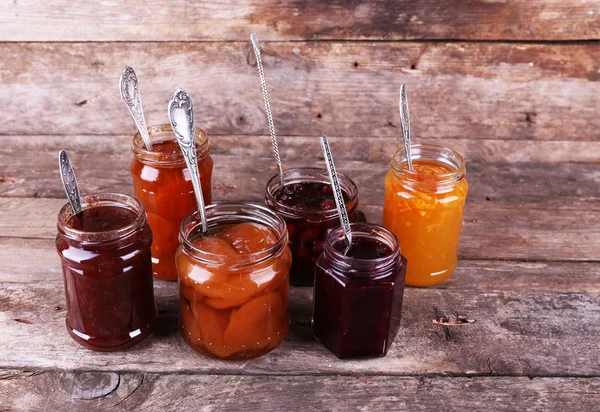 Jars of tasty jam on wooden background — Stock Photo, Image