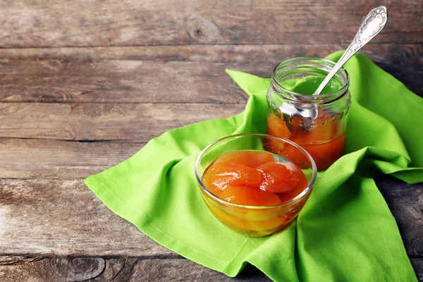 Leckere Marmelade in Schüssel und Glas mit Serviette auf Holzgrund — Stockfoto