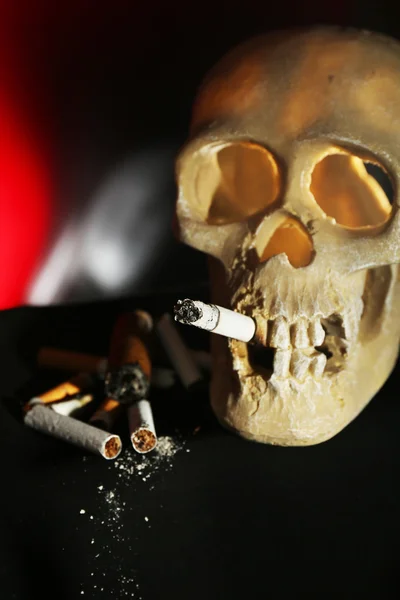 Fumar scull humano com cigarro em sua boca no fundo de cor escura — Fotografia de Stock