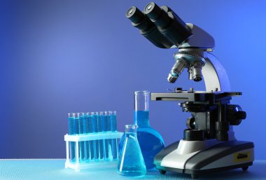 Mikroskop ve masaya renk arka plan üzerinde test tüpleri