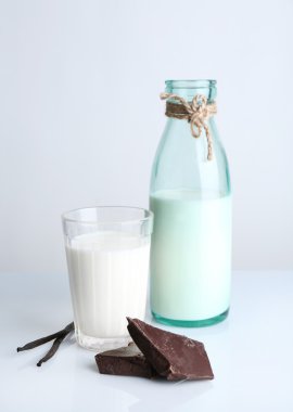 Cam ve şişe süt çikolata parçaları ve vanilya çubukları beyaz izole