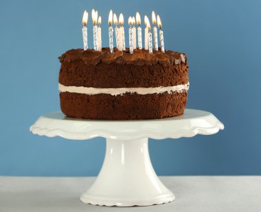 Mavi zemin üzerine masada mumlarla lezzetli çikolatalı kek