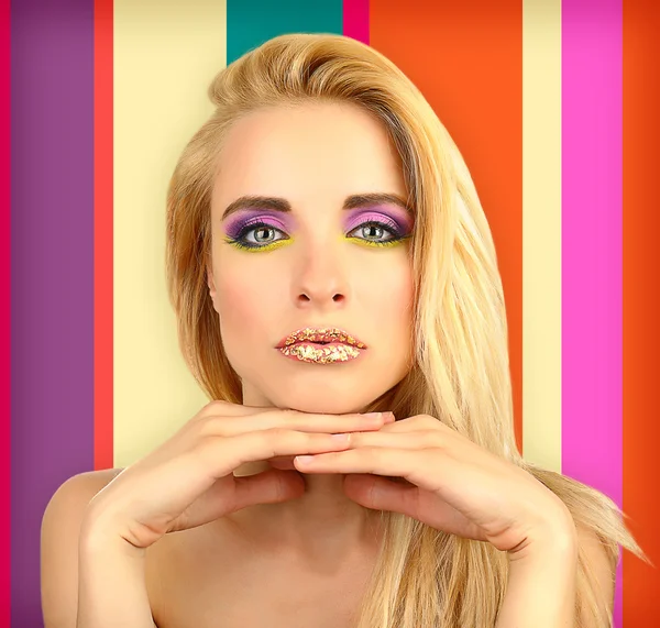 Vacker kvinna med ljusa make-up, på färgstarka bakgrund — Stockfoto