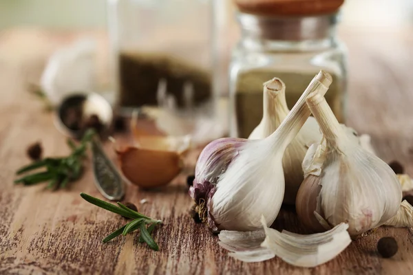 Raw garlic and spices on wooden table — Stock Photo, Image