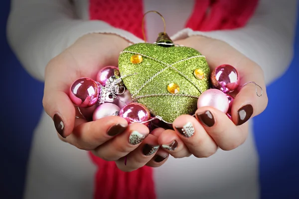 Kerst decoraties in vrouwelijke handen op kleur achtergrond — Stockfoto