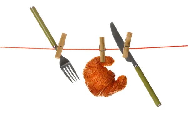 Fork, knife and croissant hanging from clothesline isolated on white background — Stock Photo, Image