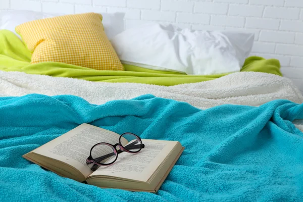 Bok och glasögon på sängen närbild — Stockfoto