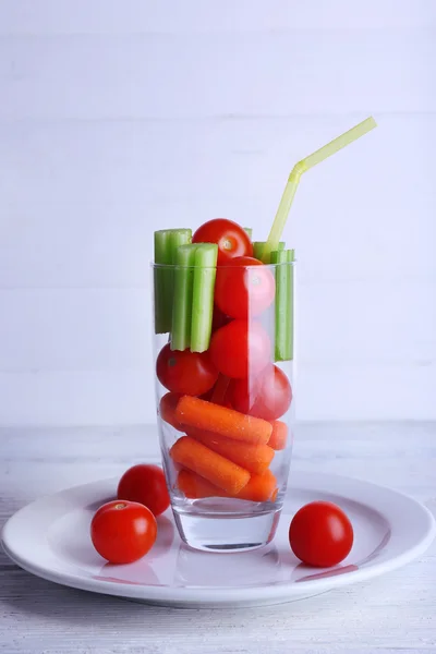 Légumes en verre avec tube sur plaque et couleur planches en bois fond — Photo