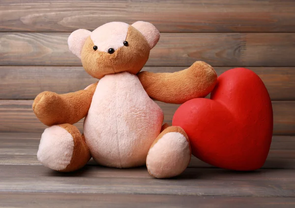 Teddybär mit rotem Herz auf hölzernem Hintergrund — Stockfoto