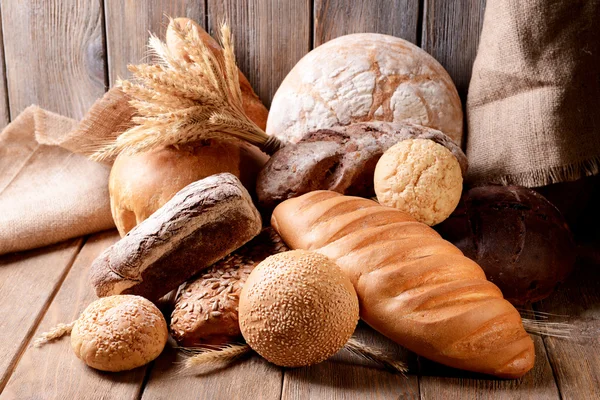 Verschillende brood op tafel op houten achtergrond — Stockfoto