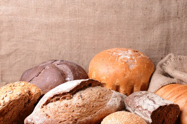 Olika bröd på bordet på säck bakgrund — Stockfoto