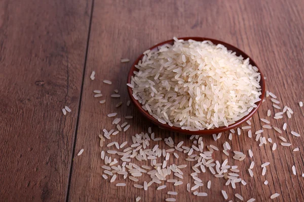 Grain de riz sur assiette sur fond en bois — Photo