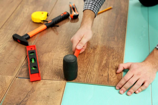 Trabalhador de carpinteiro instalando piso laminado na sala — Fotografia de Stock