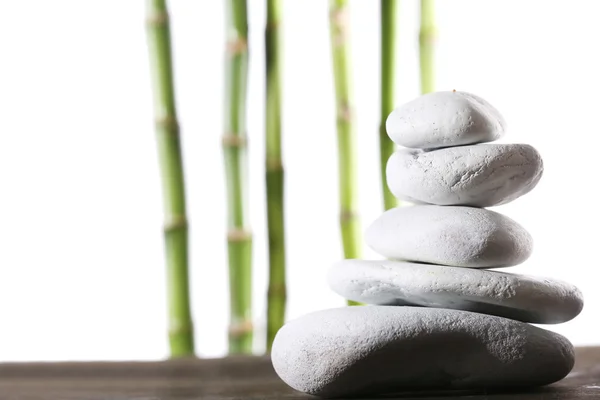 Still life of spa stones on wooden surface with bamboo sticks isolated on white — Stock Photo, Image