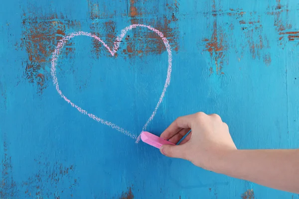 Рука рисует сердце мелом на деревянной доске — стоковое фото