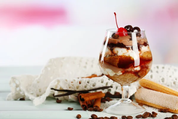 Tasty tiramisu dessert in glass, on wooden table, on light background — Stock Photo, Image