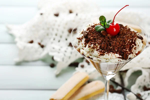 Вкусный десерт из тирамису в стакане, на салфетке, на деревянном фоне — стоковое фото