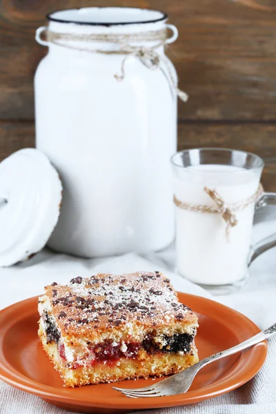 Tarte maison avec confiture et verre et boîte de lait sur nappe et fond en bois — Photo