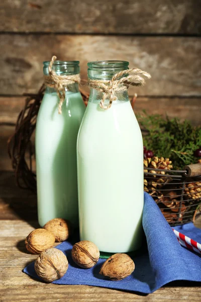 Bottles of fresh milk with natural decor, on wooden background — Stock Photo, Image