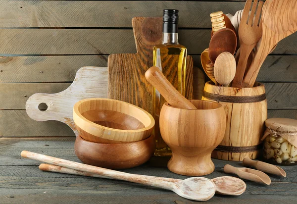 Utensilios de cocina de madera con botella de vidrio de aceite de oliva sobre tablones de madera de fondo — Foto de Stock