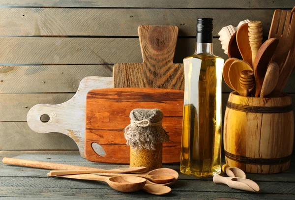 Houten keukengerei met glazen fles van olijfolie op houten planken achtergrond — Stockfoto