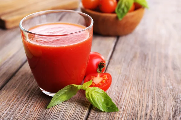 Sumo de tomate em vidro com manjericão e tomate cereja em pranchas de madeira fundo — Fotografia de Stock