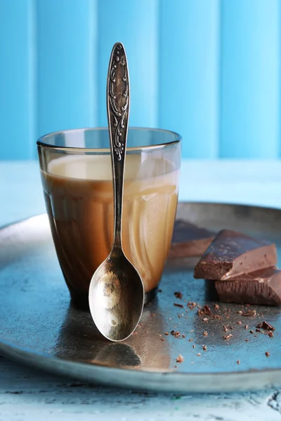 Glass of milk with chocolate chunks on metal tray and color wooden planks background — Stock Photo, Image