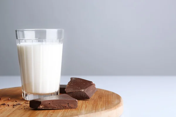 Glass of milk with chocolate chunks on wooden cutting board isolated on white — Stock Photo, Image