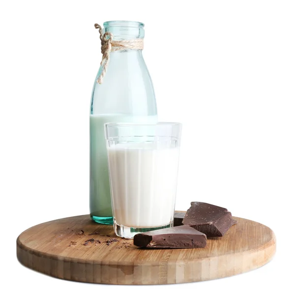 Vidrio y botella de leche con trozos de chocolate en tabla de cortar de madera aislada en blanco — Foto de Stock