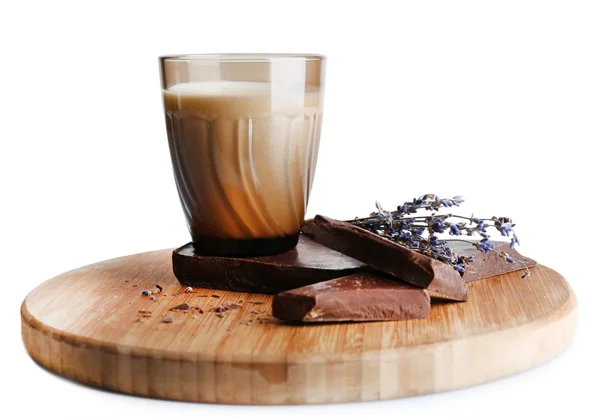 Copo de leite com pedaços de chocolate e flor seca em tábua de corte de madeira isolada em branco — Fotografia de Stock