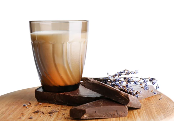 Glass of milk with chocolate chunks and dried flower on wooden cutting board isolated on white — Stock Photo, Image