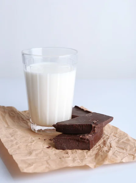 Glass of milk with chocolate chunks on sheet of crumpled paper isolated on white — Stock Photo, Image