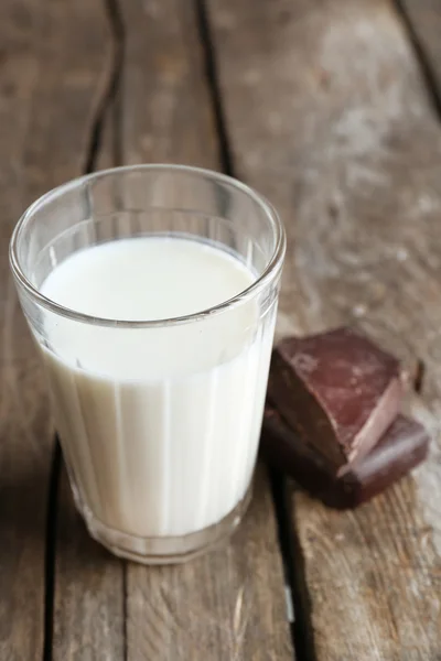 Bicchiere di latte con pezzi di cioccolato su sfondo rustico tavole di legno — Foto Stock