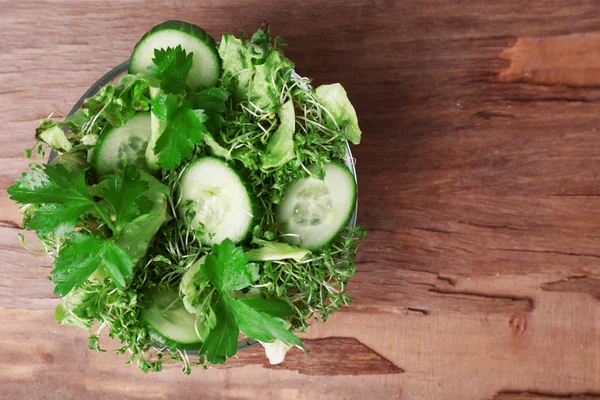 Waterkers salade met gesneden komkommer en peterselie in glazen kom op rustieke houten tafel achtergrond — Stockfoto