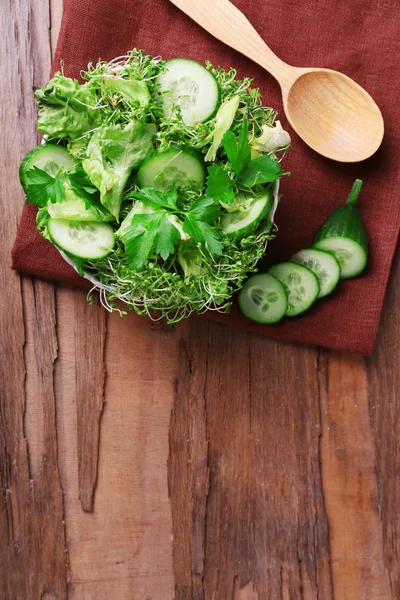 Salada de agrião com pepino fatiado e salsa em tigela de vidro no fundo da mesa de madeira rústica — Fotografia de Stock