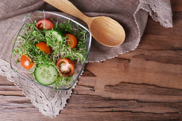 Waterkers salade met gesneden komkommer en cherry tomaten in glazen kom op rustieke houten tafel achtergrond — Stockfoto