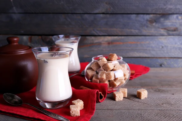 Zwarte thee met melk in glazen en theepot met forfaitaire suiker op een houten planken achtergrond kleur — Stockfoto