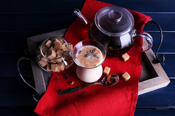 红茶牛奶和方糖上木托盘用餐巾和彩色木板背景 — 图库照片