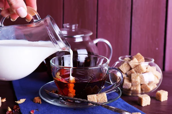 Pouring milk on tea and lump sugar — Stock Photo, Image