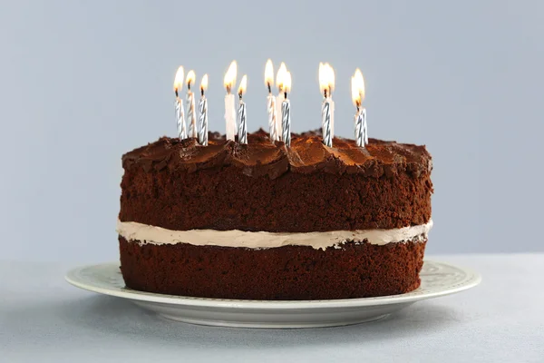 Délicieux gâteau au chocolat avec des bougies sur la table sur fond clair — Photo