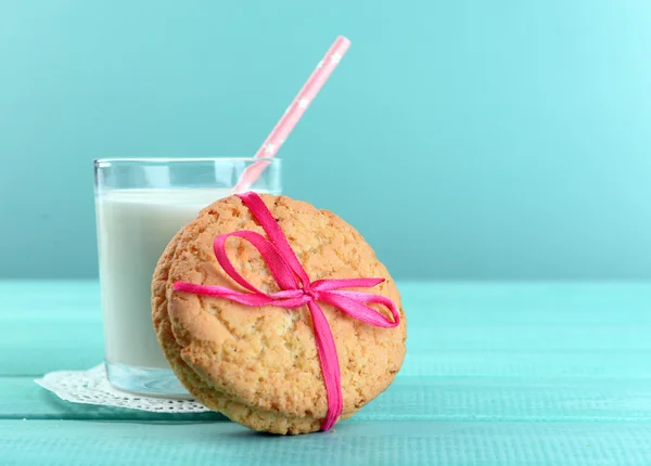 Leckere Kekse und ein Glas Milch auf farbigem Holzhintergrund — Stockfoto