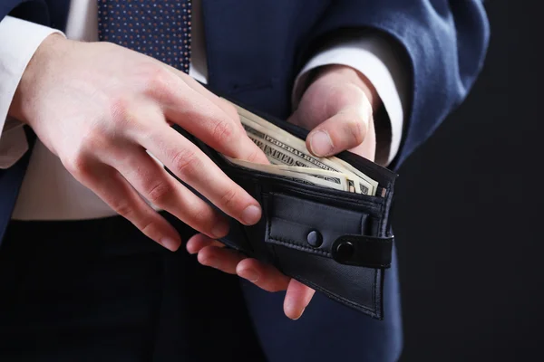 Läder plånbok med pengar i manliga händer på mörk bakgrund — Stockfoto