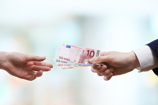 Businessman giving money on light blurred background