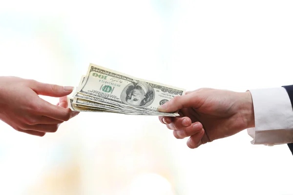 Empresário dando dinheiro em fundo embaçado luz — Fotografia de Stock