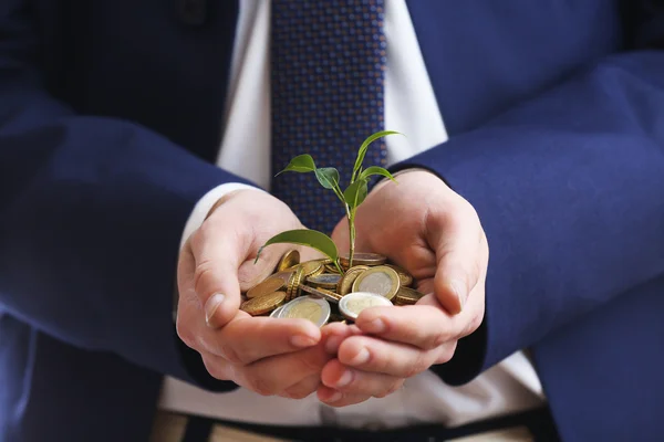 Handful of coins with growing sprout, closeup view