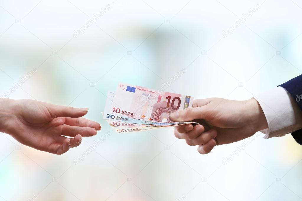 Businessman giving money on light blurred background