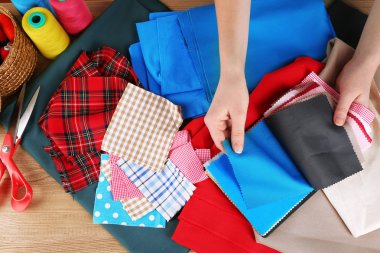 Eller ahşap masa arka plan üzerinde renkli kumaş örnekleri