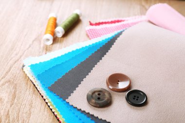 Düğmeleri ve ahşap masa arka plan iş parçacığı olan renkli kumaş örnekleri
