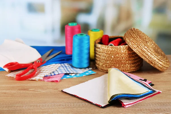 Renkli kumaş örnekleri ve ahşap masa ve hafif bulanık arka plan iş parçacığı hasır sepet — Stok fotoğraf