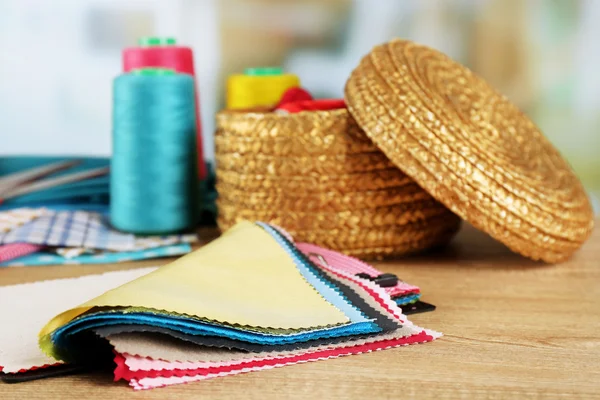 Colorful fabric samples and wicker basket of threads on wooden table and light blurred background — Stock Photo, Image